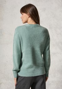 Mintgrön tröja med ribbad textur, långa ärmar och rund halsringning. Mjuk, plyschmaterial med en något lös passform vid fållen.