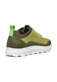 Zapatillas verdes con parte superior de punto texturizado y detalles de cuero liso. Suela blanca con un patrón de olas, que cuenta con una lengüeta verde y cordones.