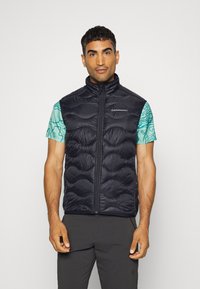 Jūras spēku pufīgs vestes korsets ar augstu apkakli, quilted dizainu un priekšējo rāvējslēdzēju, uzvilkts virs tirkīza raksta īsām piedurknēm krekla.