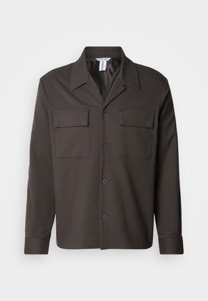 Dark brown button-up shirt with a collar, two chest pockets, and long sleeves. Made of smooth fabric with a tailored fit.