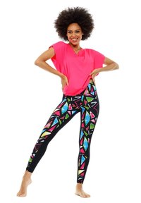 Felroze, losvallende top gecombineerd met zwarte leggings met meerkleurige geometrische patronen. Zacht materiaal, ontspannen ontwerp en volledige lengte.