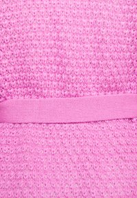 Tessuto rosa texturizzato con un motivo in rilievo e una banda rosa liscia al centro. Materiale morbido e lavorato a maglia.