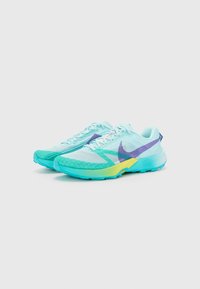 Scarpe da corsa azzurre chiare con tessuto in rete, accenti viola, suola testurizzata e una sezione gialla-verde sfumata nel tallone.