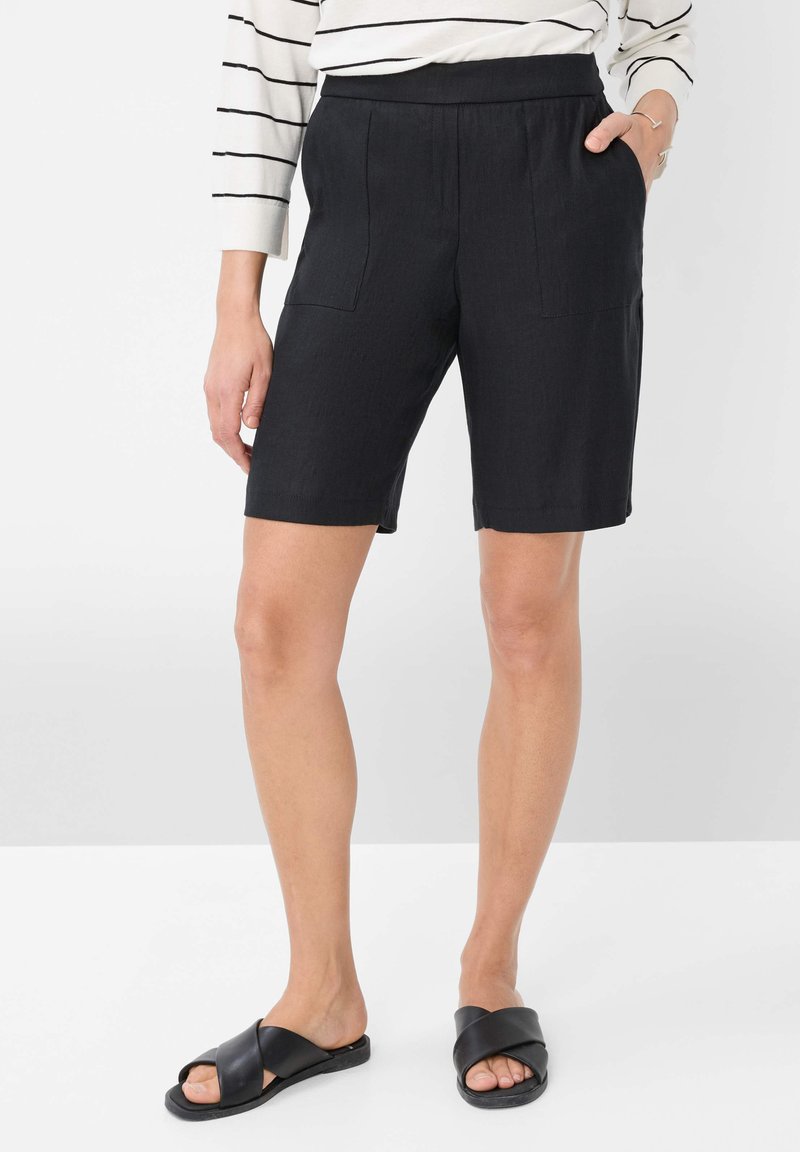 Bermuda shorts neri in lino con vita elasticizzata, due tasche anteriori e una vestibilità rilassata. Abbinati a sandali neri con cinturini incrociati.