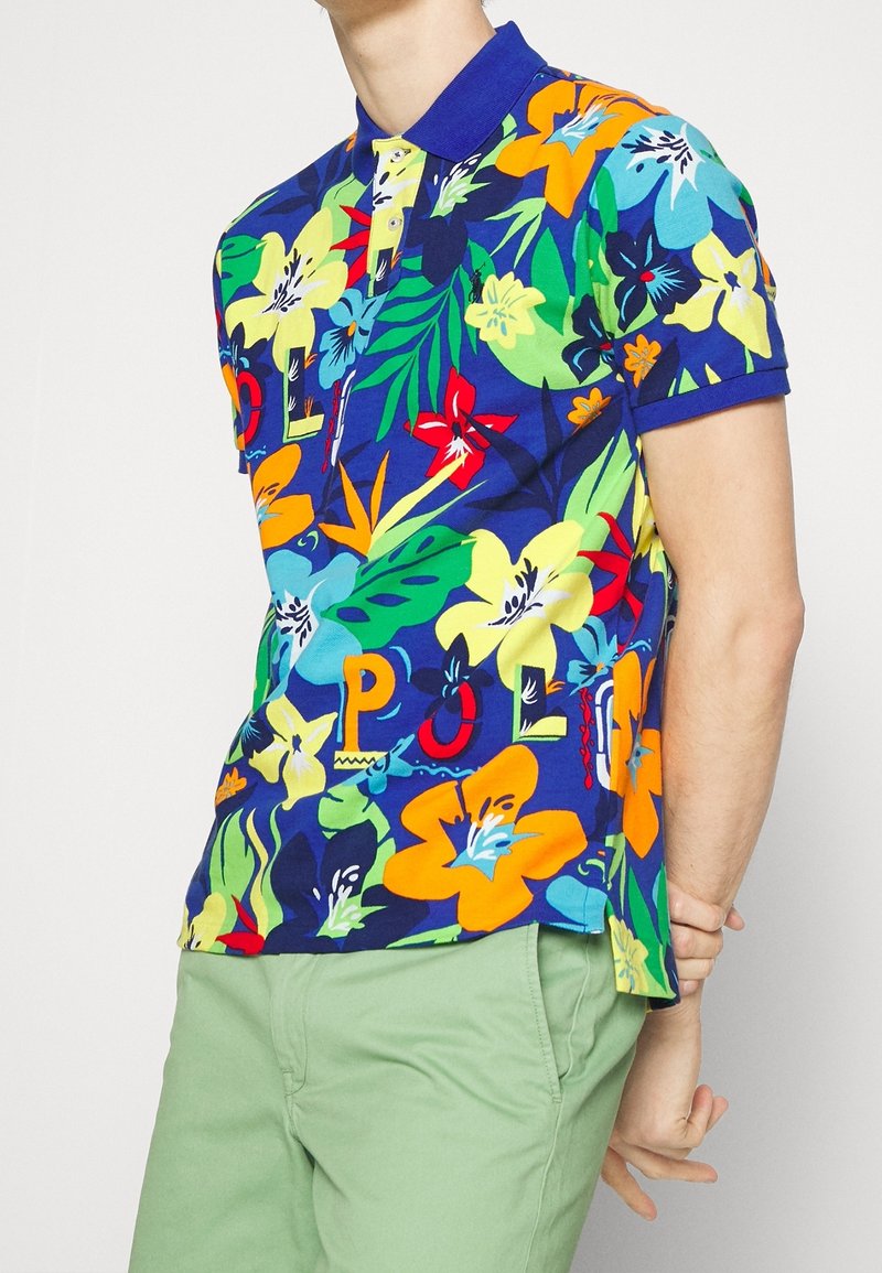 Kurzärmeliges Poloshirt mit blauem Blumenmuster und leuchtend gelben, roten und grünen Blumen, ausgestattet mit einem einfarbigen blauen Kragen und Knopfleiste.