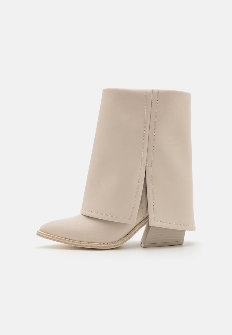 Botte en cuir beige mi-mollet avec un revers plié, un bout pointu et un talon bloc avec des coutures détaillées.