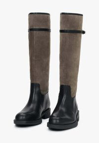 Vysoké boty s dolní částí z černé kůže a horní částí ze šedé semišové kůže, s horizontálním černým popruhem na vršku a minimem dalších detailů.