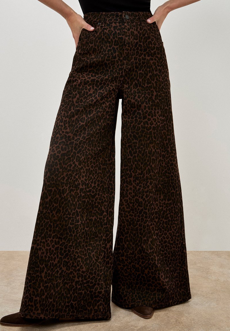 Weite Beinhosen aus dunkelbraunem Stoff mit Leopardenmuster. Die Hose hat einen hohen Bund, seitliche Taschen und wird mit einem Knopfverschluss abgeschlossen.