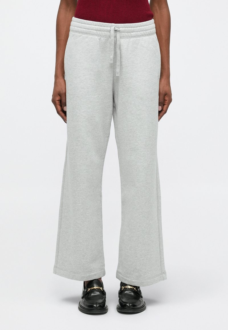 Gai pelēki treniņbikšu ar platām kājām, elastīgu jostu un auklu. Izgatavotas no mīksta, teksturēta auduma.