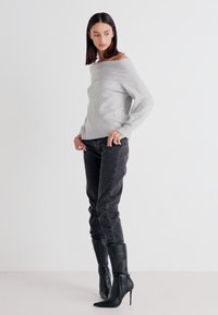 Gray off-shoulder sweater, tapered black pants, and black heeled boots with ribbed texture. Simple and contemporary design.