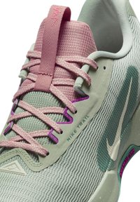 Nike trail løbesko i lysegrøn og pink. Funktioner inkluderer en tekstureret overdel, kontrasterende snørebånd og logo accenter i hvid og lilla.