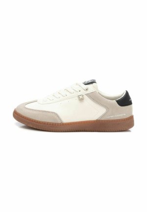 Zapatilla blanca y beige con suela de goma, acentos de ante, punta redonda y cierre de cordones. Presenta una tab de talón negra y un detalle del logotipo gris.