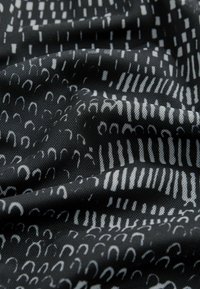 Sort stof med hvide geometriske mønstre, herunder stregede linjer og buer, med en glat tekstur og foldet udseende.