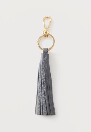 Porte-clés en cuir gris avec pompon, anneau métallique doré et fermoir sur un fond clair uni.