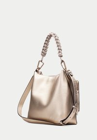 Metallic guld läderhandväska med en avslappnad form, texturerad yta och flätad topphandtag. Har en avtagbar axelrem.