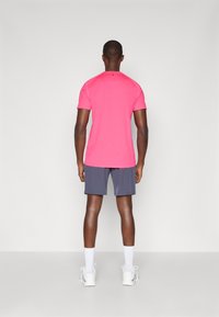 Ροζ αθλητικό μπλουζάκι, κοντά μανίκια, λεία υφή. Συνδυασμένο με γκρι σορτς, που φτάνουν μέχρι το μεσαίο άνοιγμα του μηρού. Λευκά αθλητικά παπούτσια και κάλτσες crew ολοκληρώνουν την εμφάνιση.