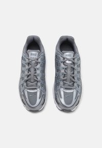 Szürke sportcipők hálós és szintetikus anyagból, fűzőrendszerrel, párnázott bokaléccel és fényvisszaverő díszítésekkel. Nike logó a nyelvén.