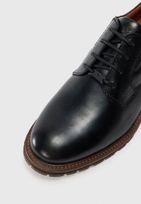 Scarpa da uomo in pelle nera con punta tonda, chiusura con lacci, suola cucita marrone e logo impresso sulla linguetta e nei dettagli dei lacci.