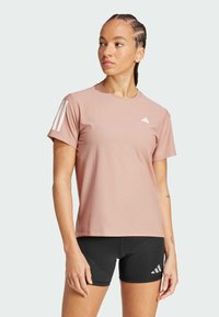 Lichtroze sportt-shirt gemaakt van vochtregulerend materiaal, met drie witte strepen op de linkerschouder en een klein logo op de borst.
