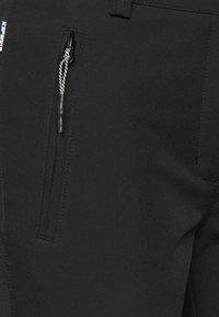Czarne spodnie o gładkiej fakturze, z zamkniętą kieszenią po boku i detalem ze sznurkiem do zapięcia. Stitched seams zwiększają trwałość.