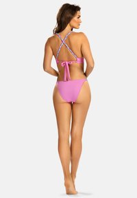 Różowy bikini z krzyżowanym plecakiem, z plecionymi ramiączkami i wiązaniem z tyłu. Gładki materiał z minimalnym zakryciem.