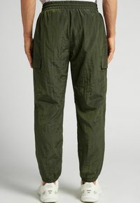Groene nylon cargobroek met een gestructureerde afwerking, elastische tailleband en enkels; voorzien van zijcargozakken voor extra opbergruimte.