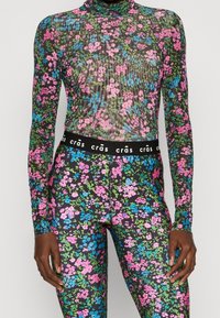Langærmet blomster bodysuit og matchende leggings. Gennemsigtigt sort materiale med flerfarvede rosa, blå og grønne blomster mønstre. Elastisk talje.
