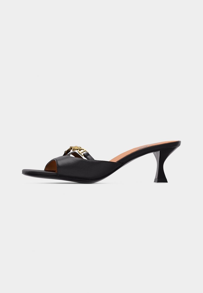 Mule en cuir noir à bout ouvert avec petit talon courbé et chaîne décorative dorée sur la bride supérieure.