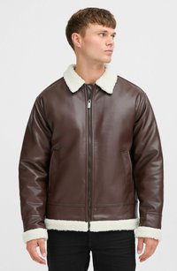 Chaqueta de cuero marrón con un cuello y puños de sherpa blancos, que presenta un cierre frontal de cremallera y dos bolsillos laterales. Textura suave, diseño hasta la cadera.