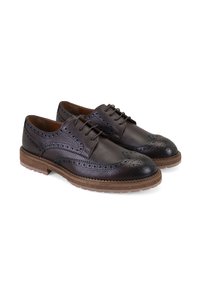 Brogues en cuir marron foncé avec une finition texturée, présentant des détails perforés, des lacets plats et une semelle en caoutchouc contrastante.