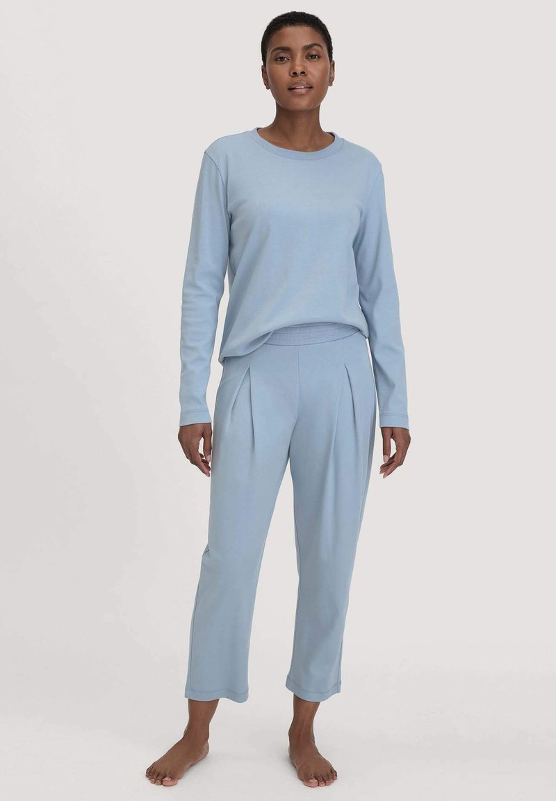 Hellblaue Loungewear-Set mit einem langärmeligen Oberteil mit Rundhalsausschnitt und lockerem Schnitt sowie passenden, tapered Hosen mit Falten.