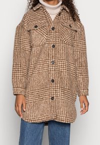 Camisa de cuadros marrón hecha de una mezcla de lana texturizada, con grandes bolsillos en el pecho, cierre de botones y un ajuste relajado.