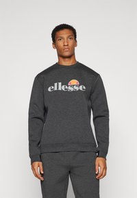 Tamno siva dukserica izrađena od mekanog materijala, s okruglim izrezom i elastičnim manžetama, s "ellesse" logotipom i obojenim akcentom iznad.