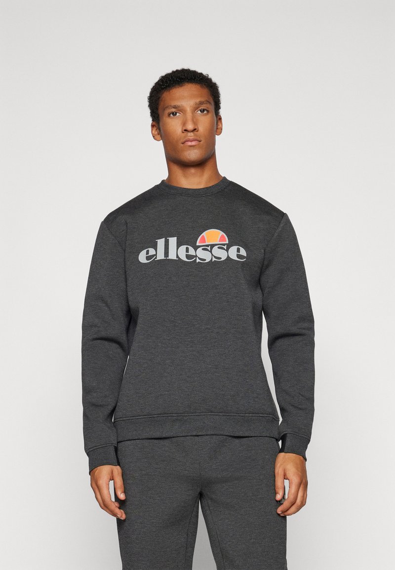 Tamno siva dukserica izrađena od mekanog materijala, s okruglim izrezom i elastičnim manžetama, s "ellesse" logotipom i obojenim akcentom iznad.