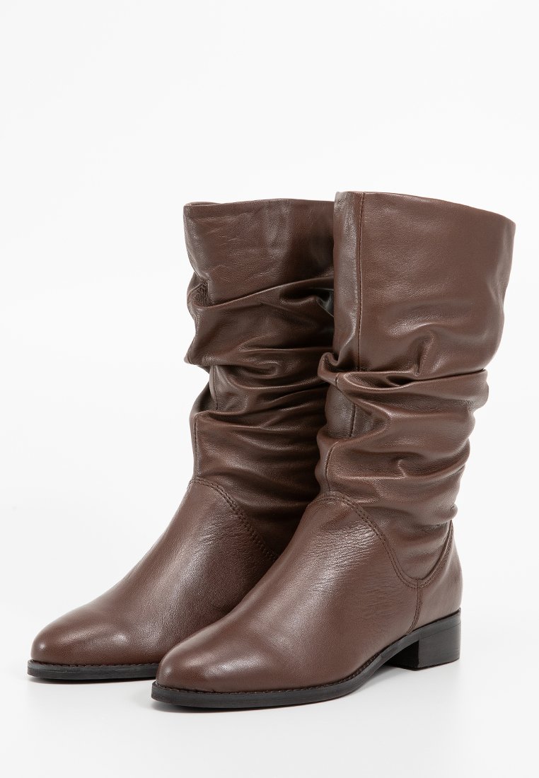 Brown leather ankle boots with a slouchy design, pointed toe, and low block heel, featuring a soft texture and minimal stitching.
