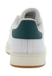 Sneaker bianco con tomaia in pelle strutturata e un accento teal sul tallone, dotato di una suola in gomma con fondo marrone chiaro.