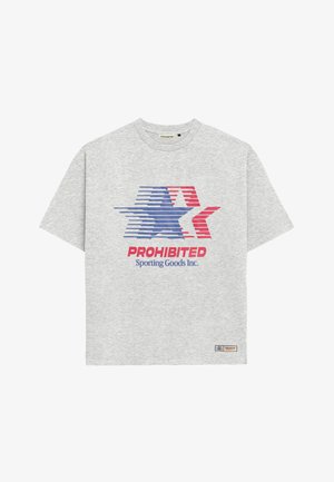 Uomo che indossa una maglietta grigia e un cappellino da baseball crema, entrambi con un logo a stella rossa e blu e la scritta "PROHIBITED Sporting Goods Inc.".