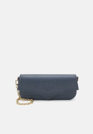 Marineblå læderclutch med en guldkædetaske, der har et præget øjendesign på forsiden og en foldet klaffelukning.