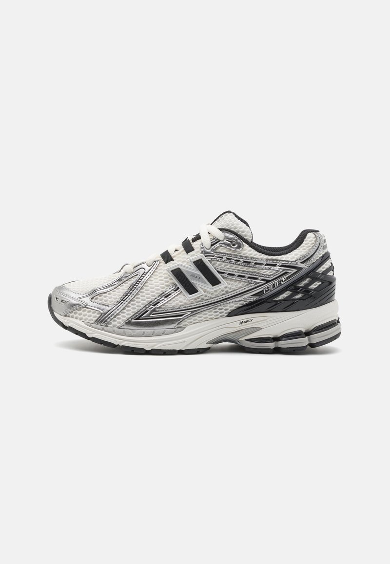 Chaussure de course New Balance blanche et argentée avec des accents noirs, dessus en mesh, semelle amortie et le logo "N" sur le côté.