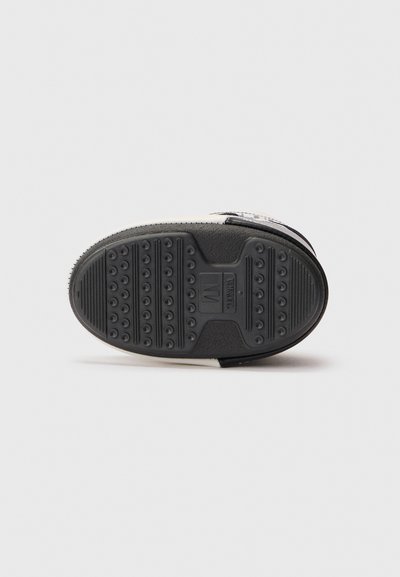 Zool van een wit sneaker met zwarte zool, voorzien van een gestructureerd grippatroon en een rechthoekig gebied gemarkeerd met "TWELVE" en maat "M" in het midden.