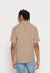 Korte mouw overhemd met bruine en witte verticale strepen, een button-down kraag en een relaxte pasvorm. De stof lijkt lichtgewicht en heeft een zachte textuur.
