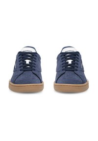 Tumši zili zamša sporta apavi ar baltām detaļām, gumijas zoli un melnām šņorēm. Aprīkoti ar perforētu purngalu un zīmola logotipu uz sāniem.