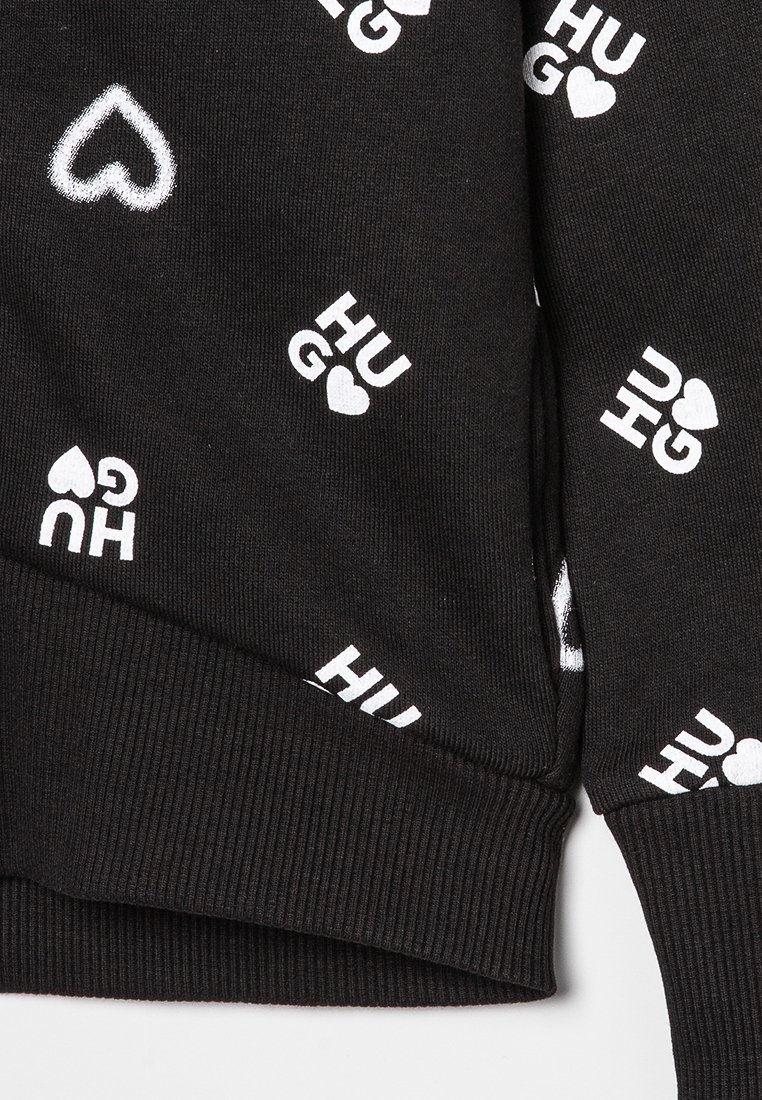 Czarny sweatshirt z białym nadrukiem tekstu i symboli serc, o teksturze i wykończeniu ze ściągaczem. Wzory obejmują słowo "HUG" i serca.