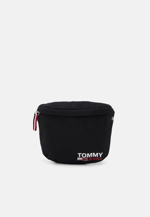 Czarna nerka Tommy Jeans z górnym zamkiem, czerwono-biało-niebieskim uchwytem suwaka i nadrukowanym logo z przodu, przedstawiona na jednolitym tle.