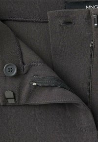 Tessuto grigio scuro con una superficie liscia; presenta un bottone e una tasca con zip, evidenziando dettagli di cucitura e un design moderno.