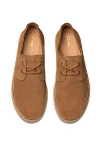 Scarpe in suede marrone con lacci, dotate di una punta arrotondata e cuciture bianche lungo il bordo. All'interno presentano una soletta beige con logo in rilievo.