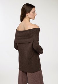 Brązowy sweter bez ramion z ribbowanym dekoltem i długimi rękawami, o miękkiej teksturze i luźnym kroju.