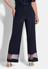 Marineblauwe wijde broek met doorzichtige mesh onderpanelen en tailleband. Gemaakt van soepele stof, met een ontspannen pasvorm en een minimalistisch ontwerp.