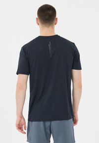 Mørkeblå kortærmet træningsskjorte med en glat tekstur, der har en vertikal reflekterende stripe detalje på den øverste ryg.