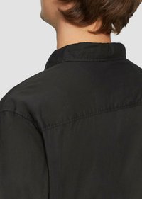 Zwarte shirt met een klassieke kraag, met een gladde textuur en subtiele stikdetails op de schouders en de rug.
